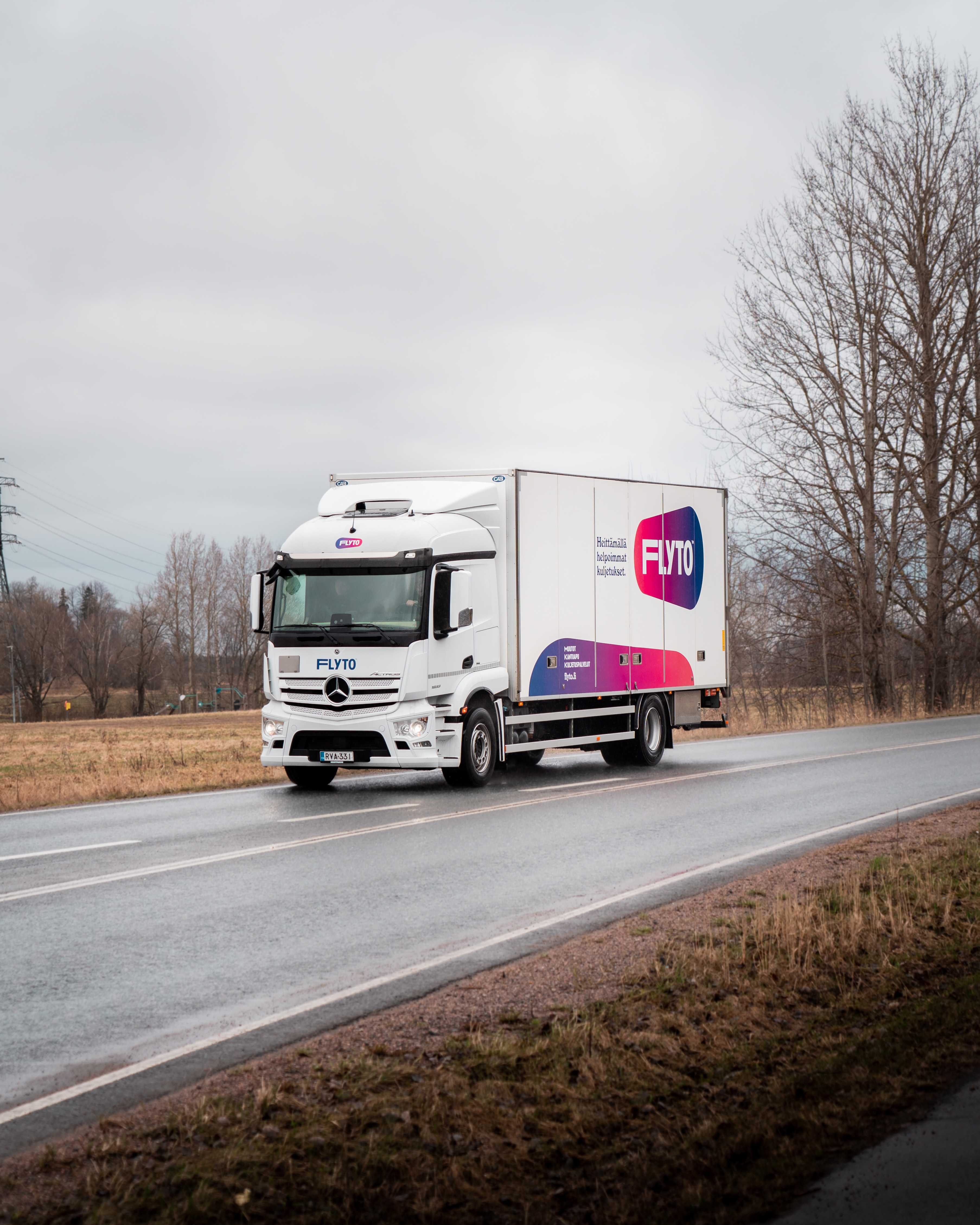 FLYTO moving truck on rural European highway with bare trees under overcast sky