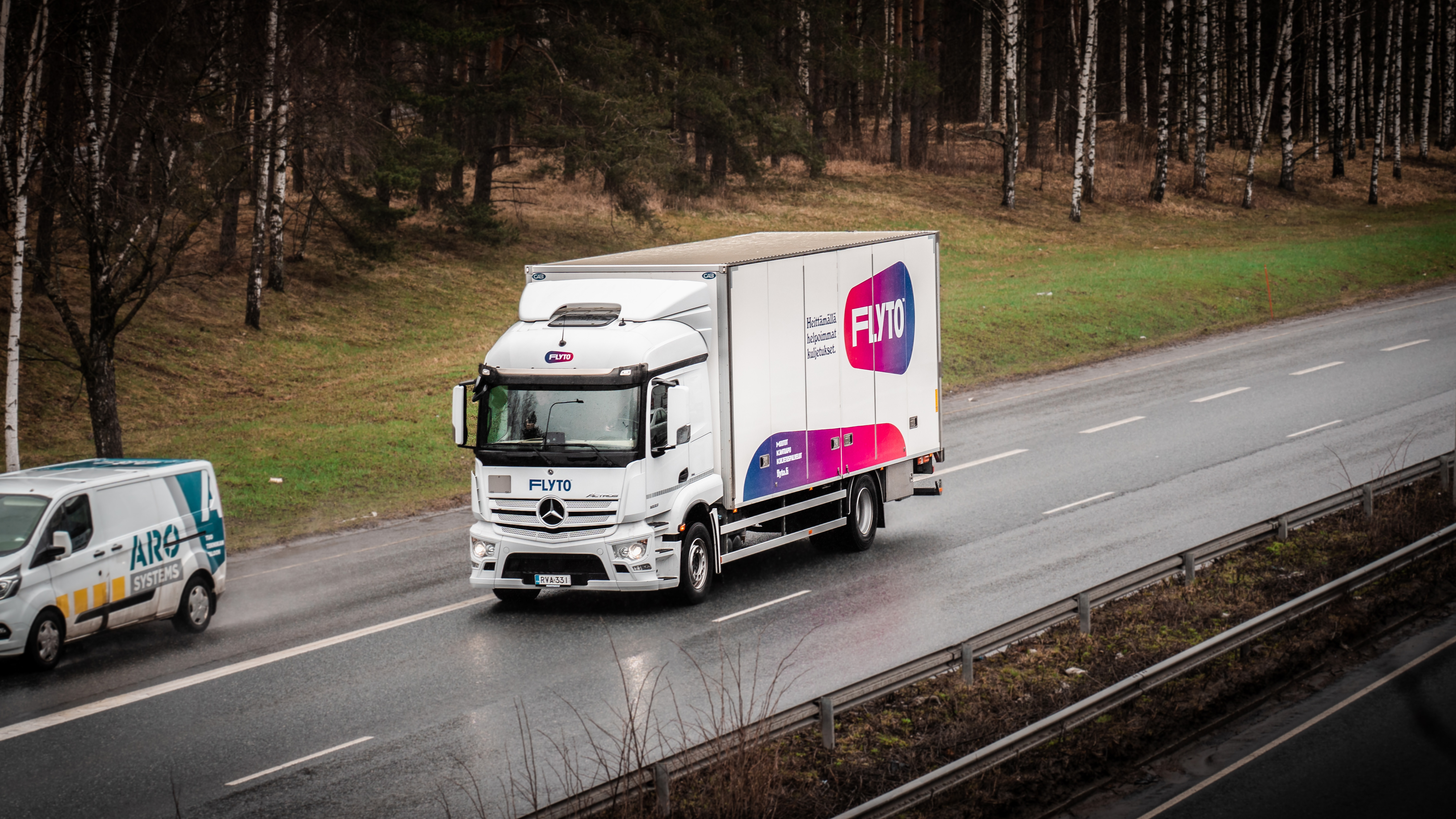 FLYTO moving truck on Nordic highway passing through birch forest