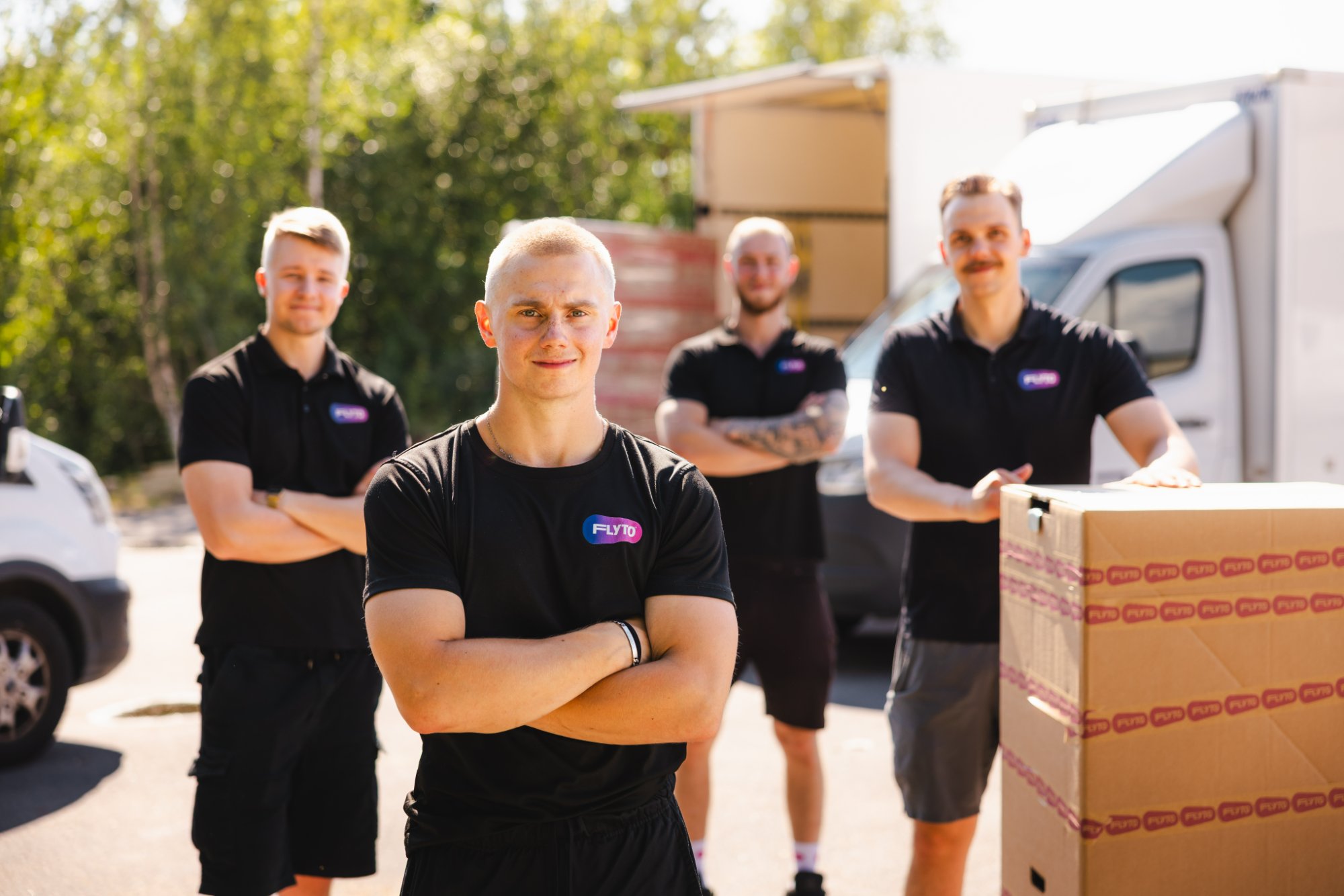 Professional moving team in uniform standing with truck and boxes ready for international relocation service