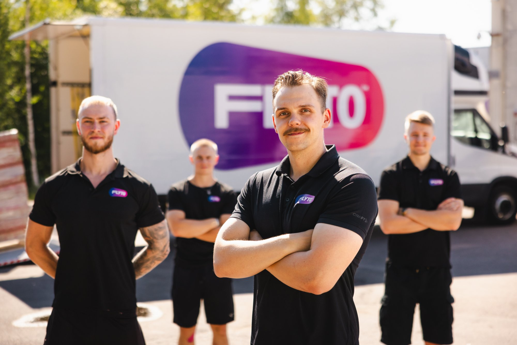 Moving company team in black uniforms standing in front of branded truck