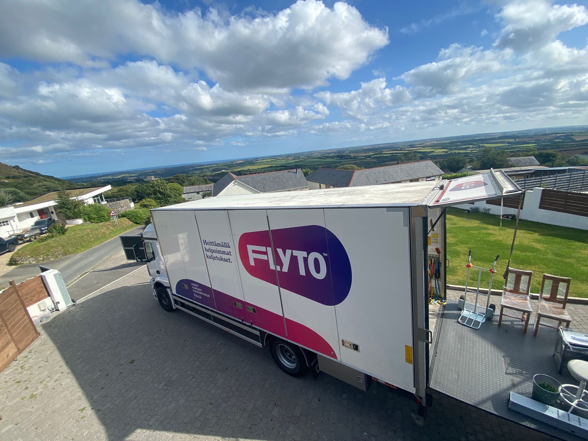 Flyto moving truck parked at residential property with countryside view