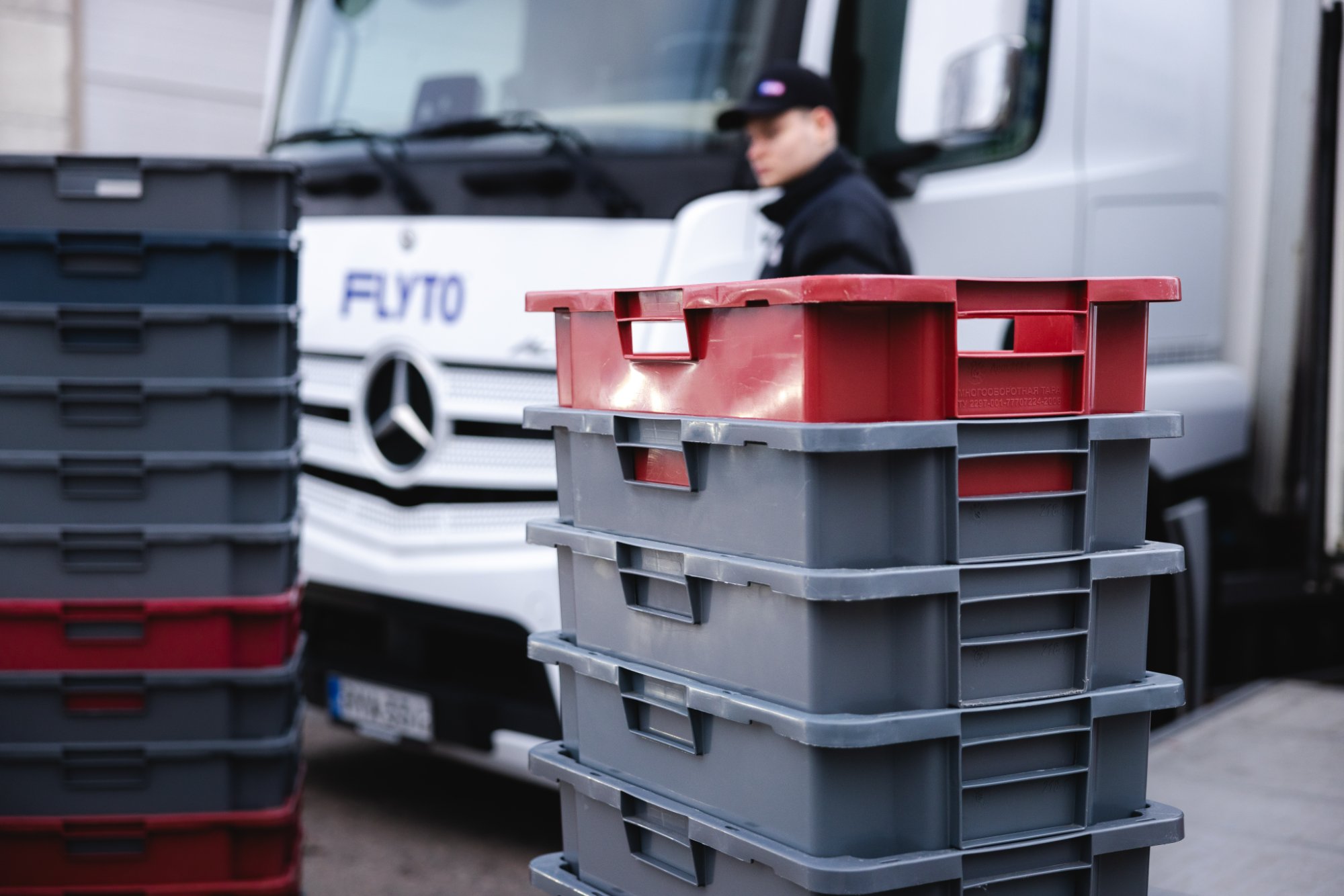 Stacked moving crates in front of FUTO branded Mercedes truck with worker