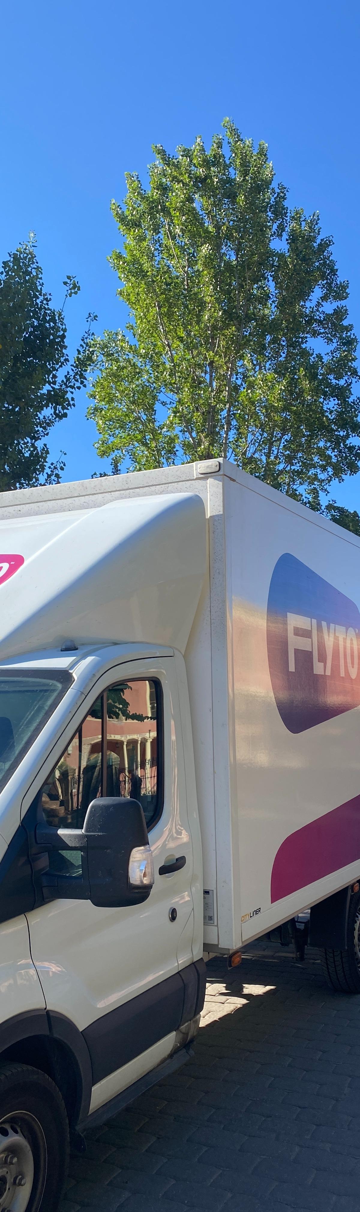 FLYTO moving truck parked near historic church with bell tower in European city