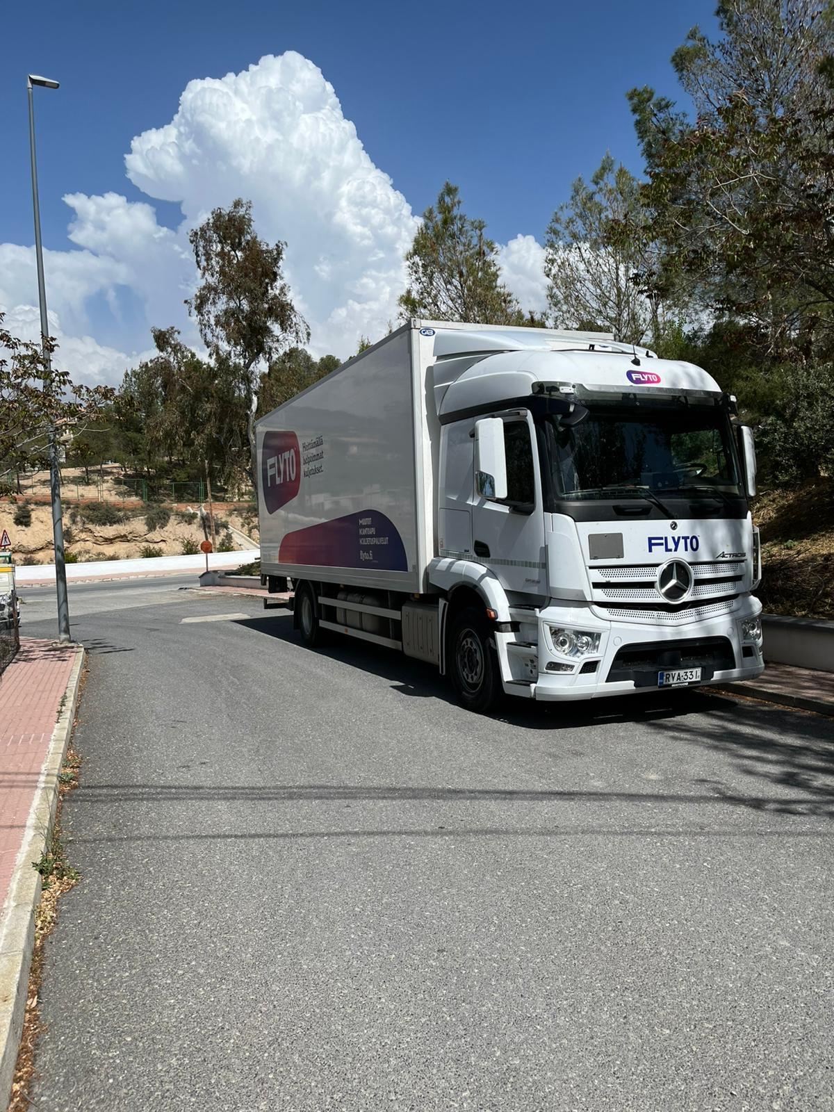 Flyto international moving truck on sunny residential street with trees and blue sky