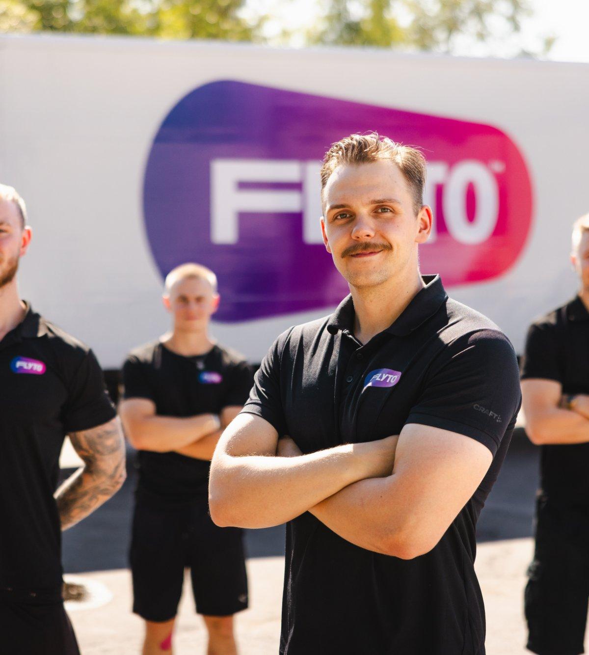 Moving company team in black uniforms standing in front of branded truck