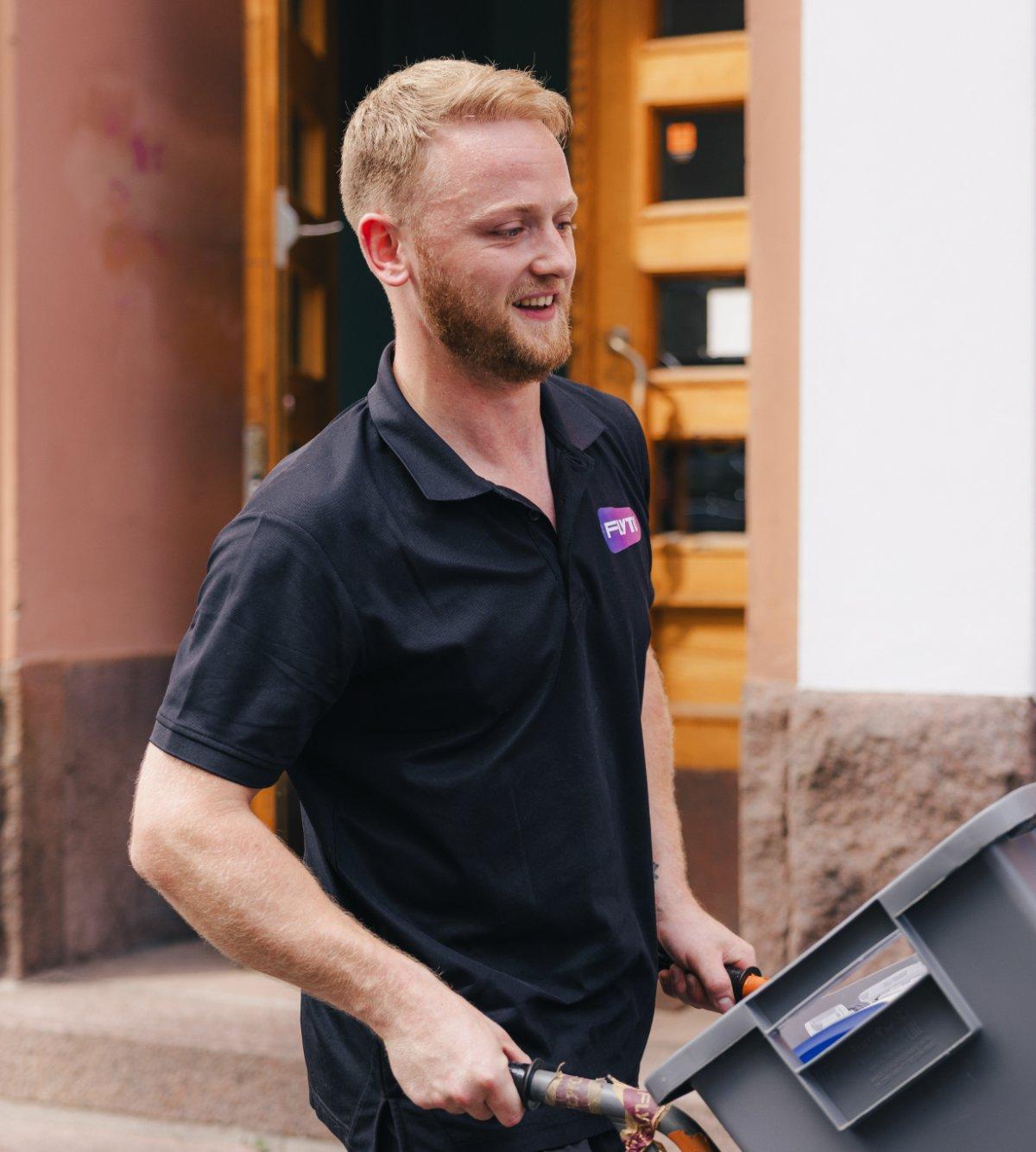 Professional mover carrying plastic moving box in front of residential building