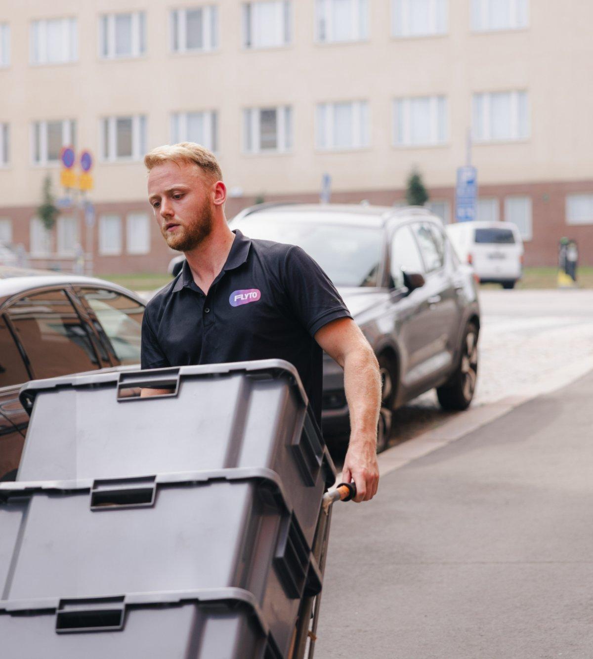 Moving company employee with dolly cart on residential street with apartment building